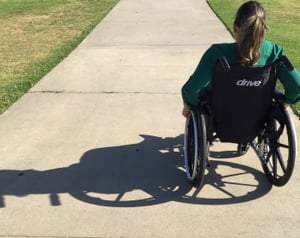 A woman in a wheelchair on a sidewalk.